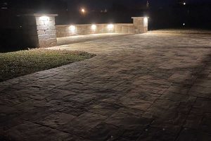backyard-stone-paver-patio-with-bench-lighting-night-photo-daltons-sprinklers-drainage-and-lighting-foley-alabama