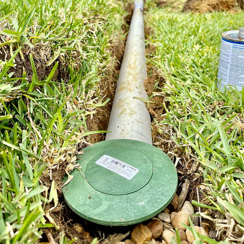 drainage pipe connected to house gutters buried in yard with popup at end for water to flow out